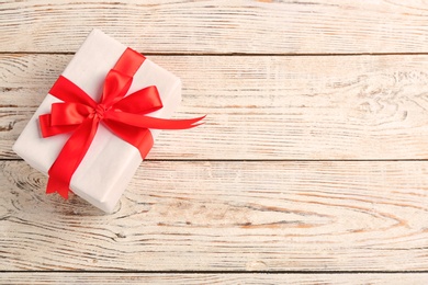 Elegant gift box with bow on wooden background, top view