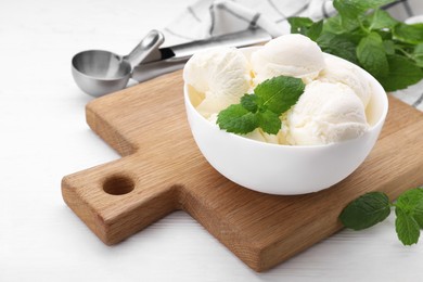 Delicious vanilla ice cream, mint and scoop on white wooden table, closeup. Space for text
