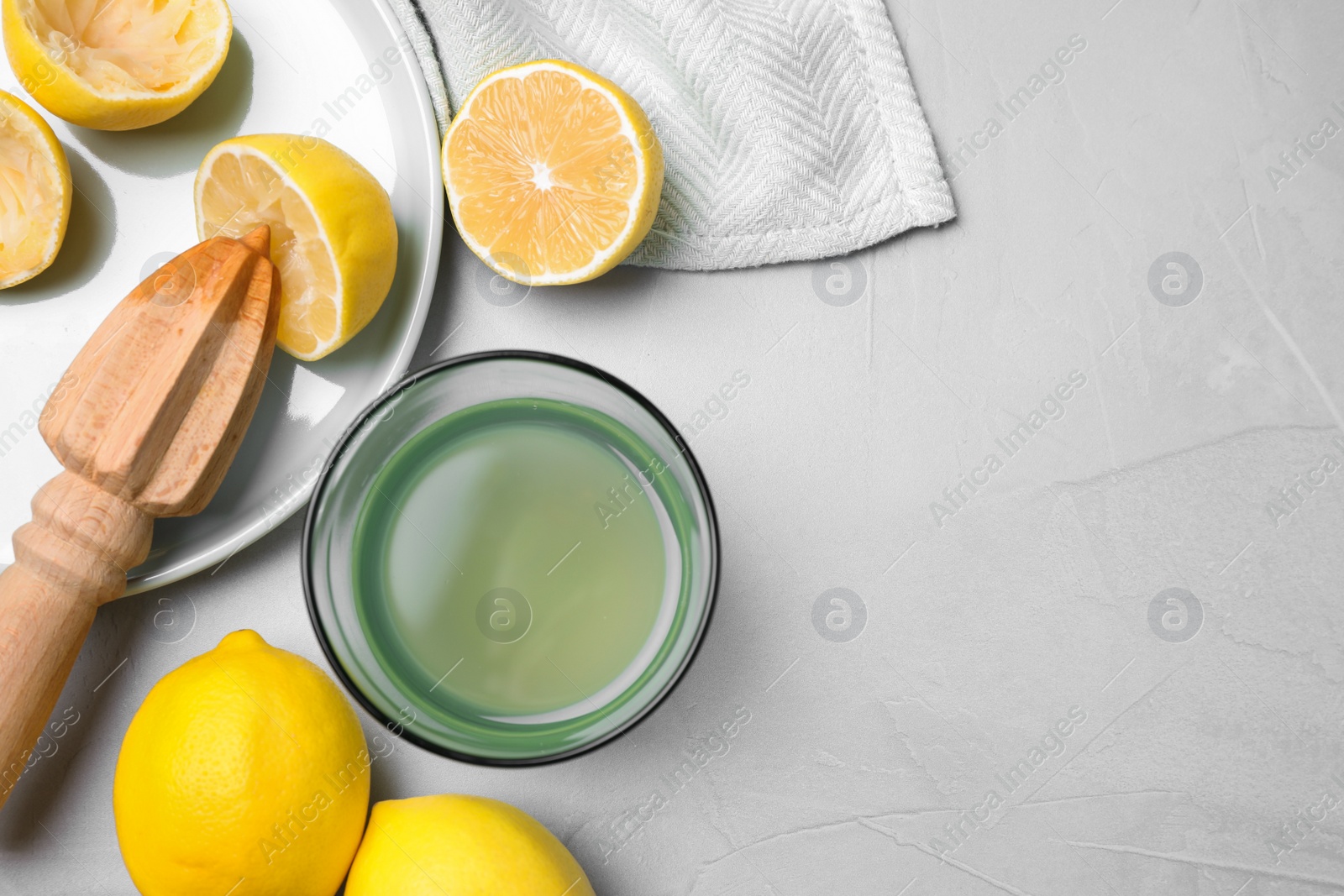 Photo of Flat lay composition with freshly squeezed lemon juice on table. Space for text