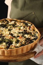 Woman holding delicious homemade spinach quiche, closeup