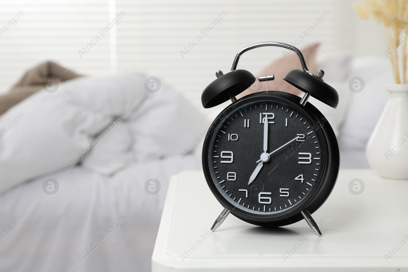 Photo of Black alarm clock on white wooden nightstand in bedroom, space for text