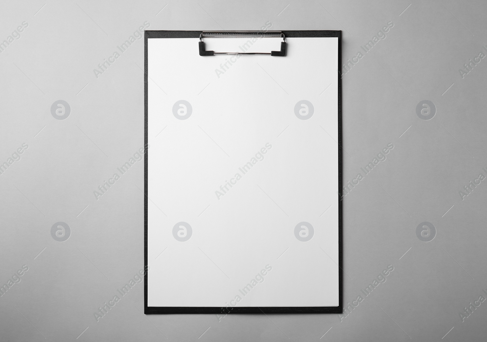 Photo of Black clipboard with sheet of blank paper on light grey background, top view