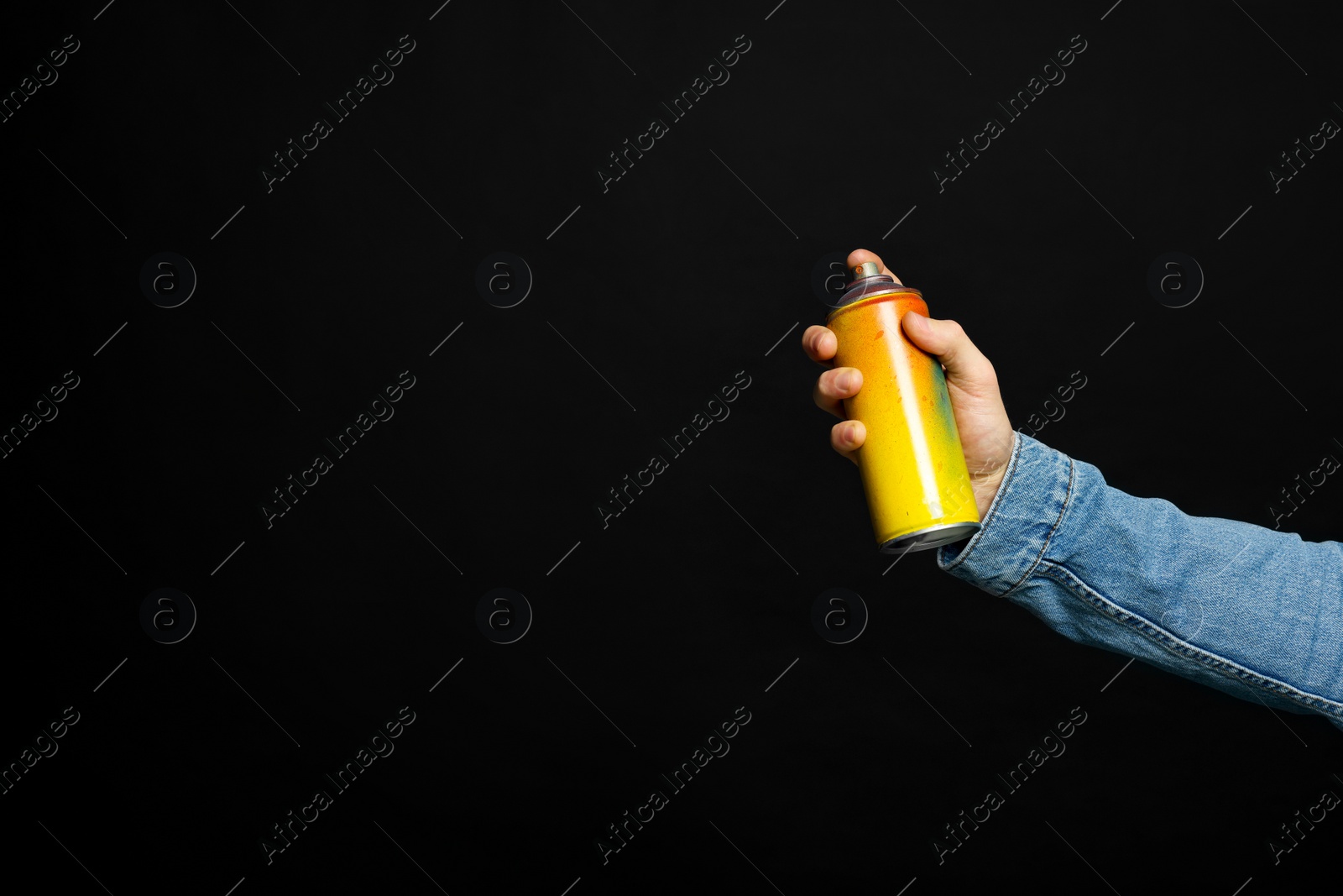 Photo of Man holding used can of spray paint on black background, closeup. Space for text