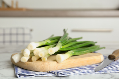 Fresh green spring onions on wooden board, closeup