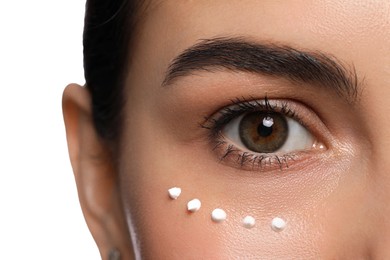 Photo of Closeup view of young woman with cream on skin under eye against white background