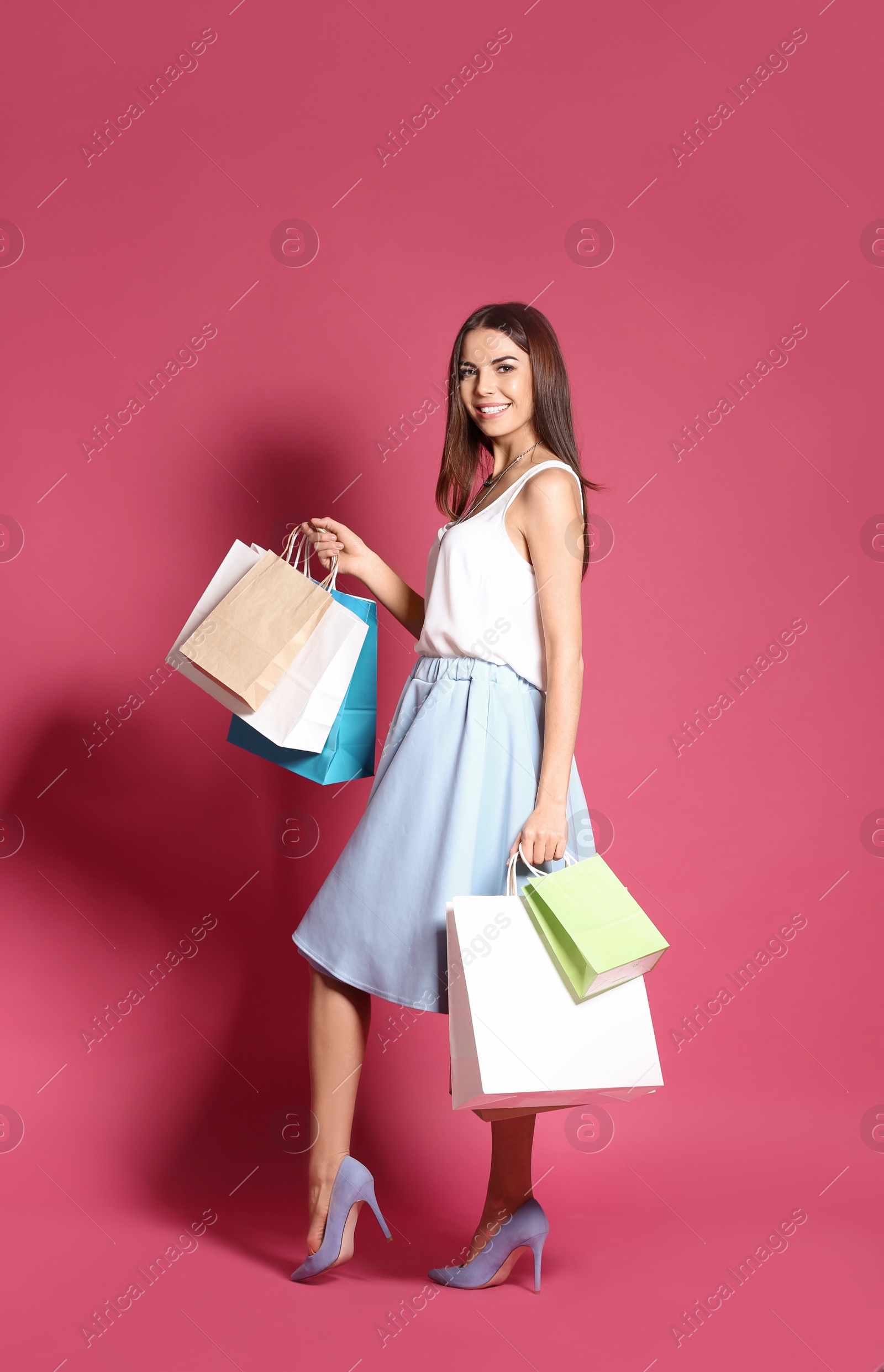 Photo of Young woman with shopping bags on color background