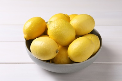 Many fresh ripe lemons on white wooden table