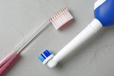 Electric and manual toothbrushes on gray background