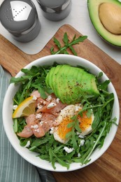 Photo of Delicious salad with boiled egg, salmon and avocado served on white wooden table, flat lay