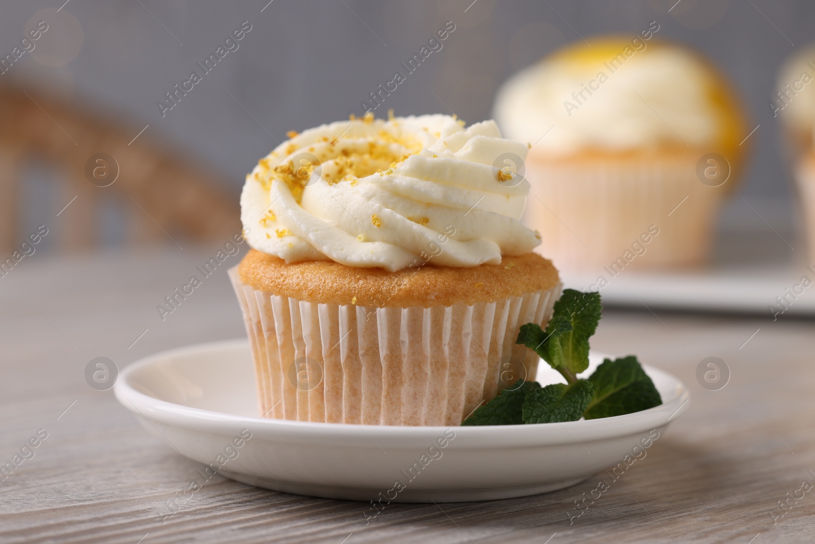 Photo of Delicious lemon cupcake with white cream and mint on table, closeup