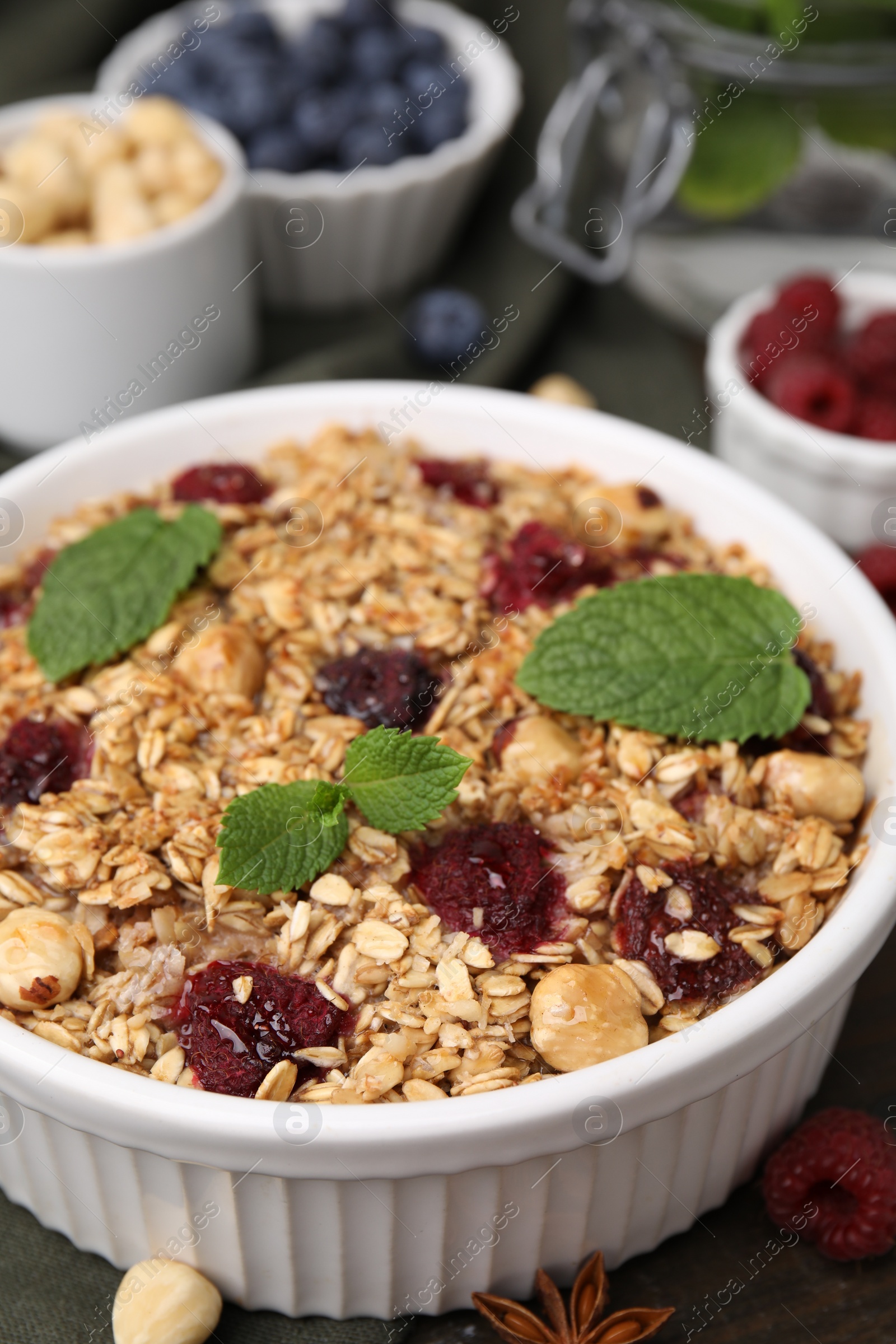 Photo of Tasty baked oatmeal with berries and nuts on wooden table, closeup