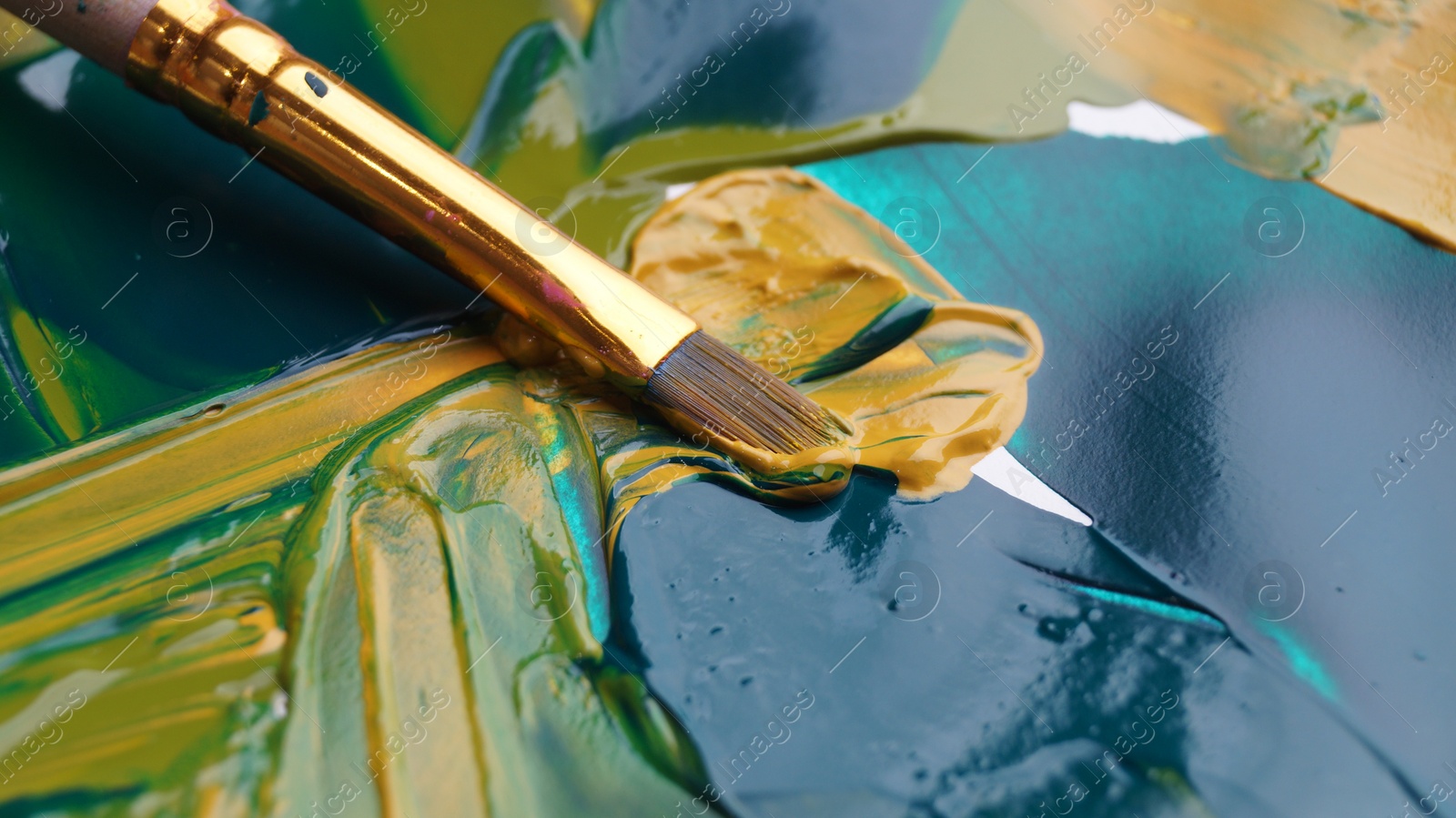 Photo of Brush on artist's palette with mixed paints, closeup