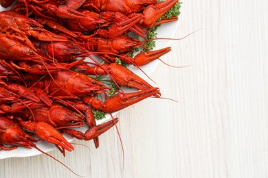 Photo of Plate with delicious red boiled crayfish on white wooden table, top view. Space for text