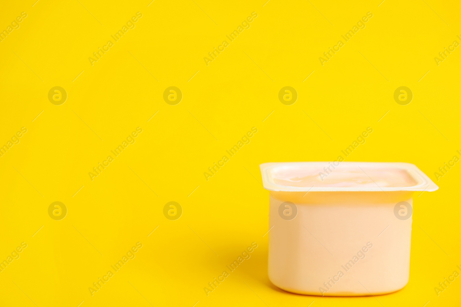 Photo of Tasty organic yogurt on yellow background. Space for text