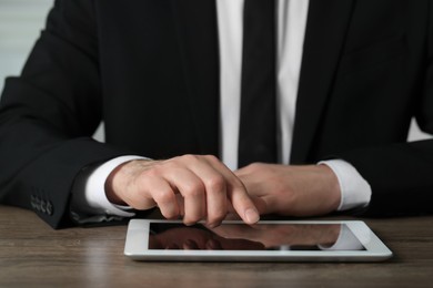 Closeup view of man using new tablet at wooden desk indoors