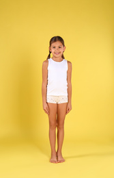 Photo of Cute little girl in underwear on yellow background
