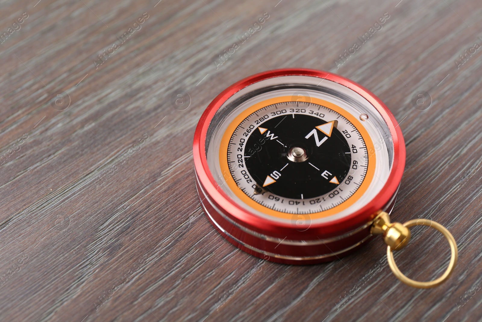 Photo of One compass on wooden table, closeup. Space for text