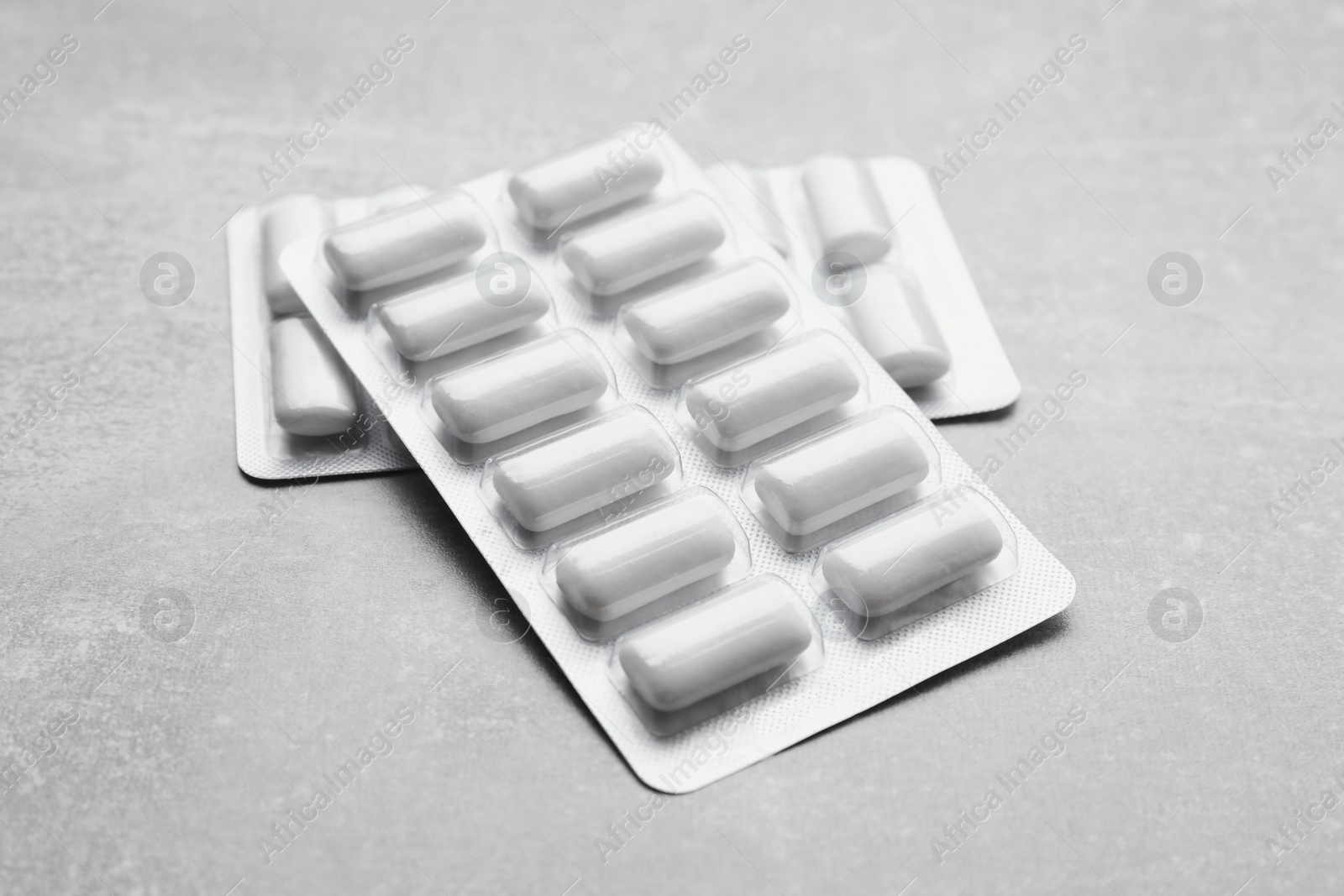 Photo of Blisters with chewing gums on light grey table, closeup