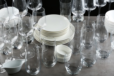 Photo of Set of empty glasses and dishware on grey table