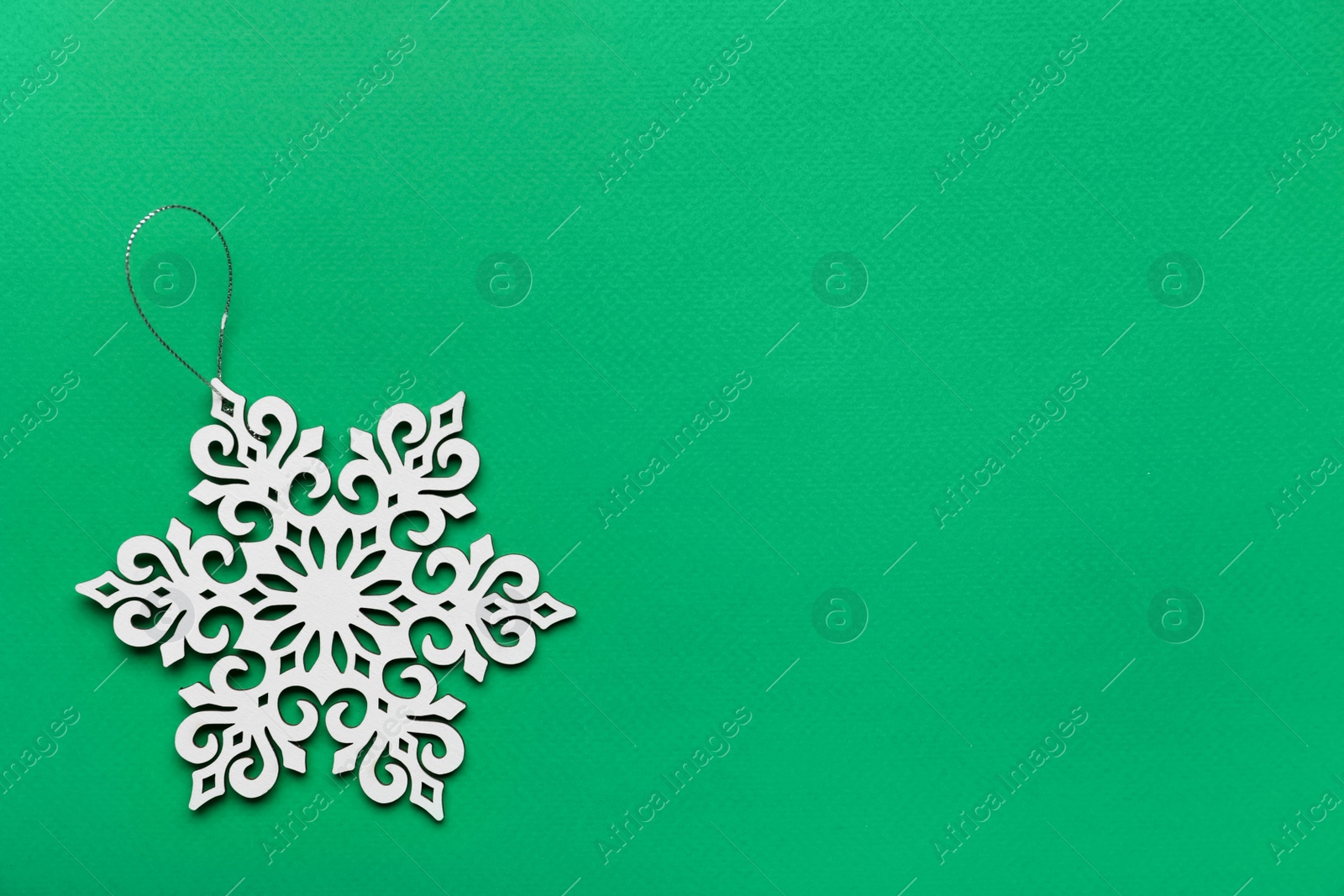 Photo of Beautiful decorative snowflake on green background, top view. Space for text