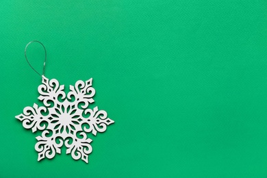 Photo of Beautiful decorative snowflake on green background, top view. Space for text
