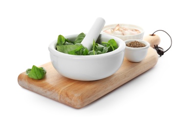 Mortar with fresh green basil leaves and bowls of spices on white background