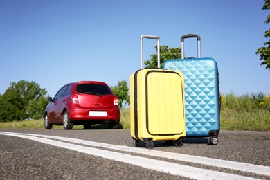 Photo of Color suitcases near family car on highway. Summer vacation