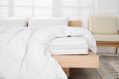 Photo of Wooden bed with soft white mattress, blanket and pillows indoors