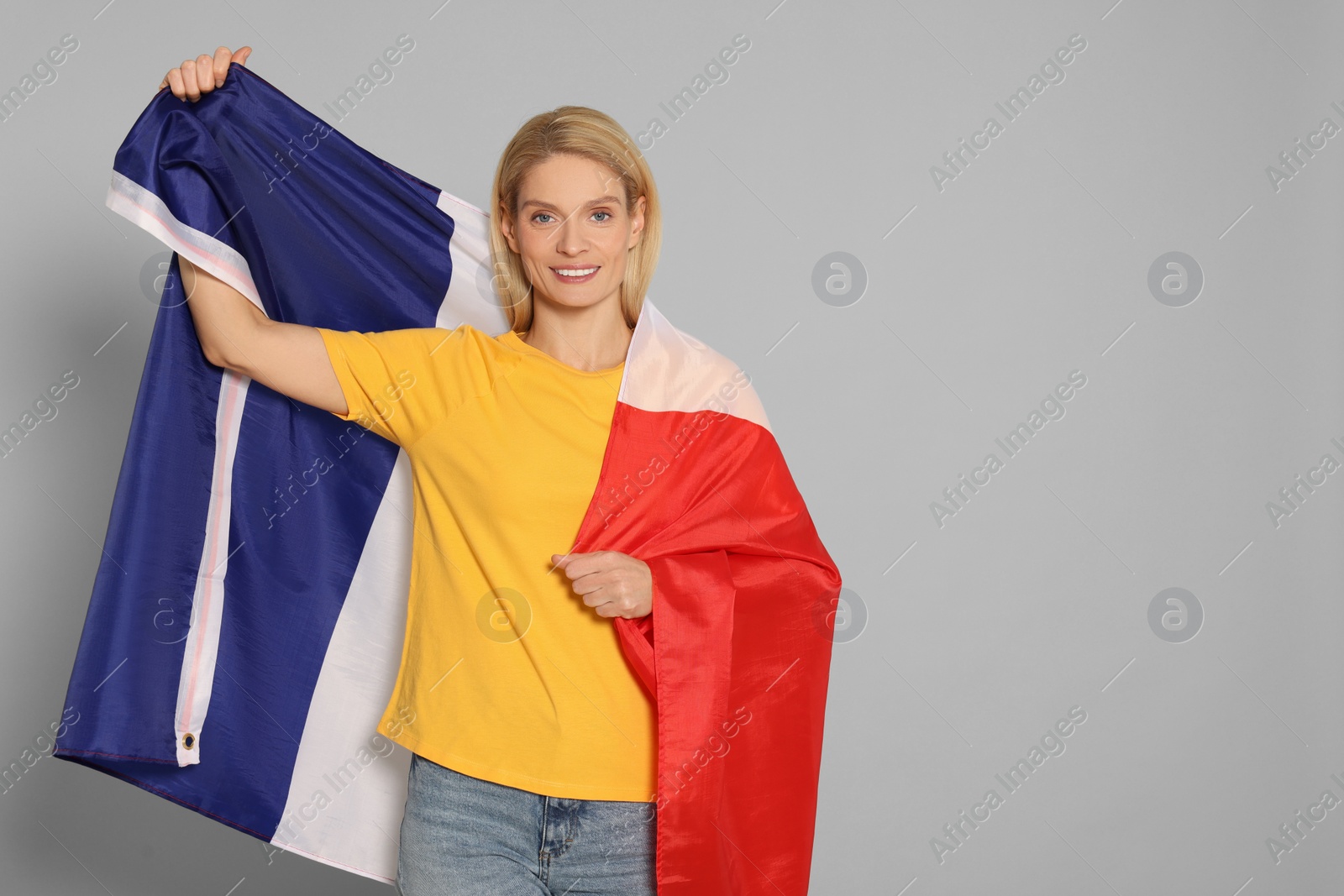 Photo of Woman with flag of France on light grey background, space for text