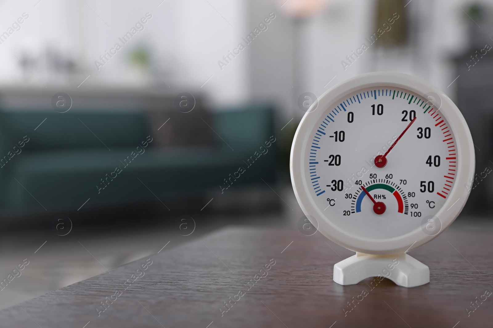 Photo of Round mechanical hygrometer on wooden table in room. Space for text