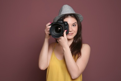 Photo of Female photographer with professional camera on color background