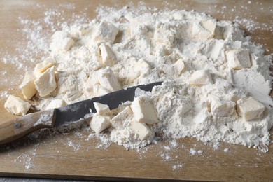 Photo of Making shortcrust pastry. Flour, butter and knife on wooden board