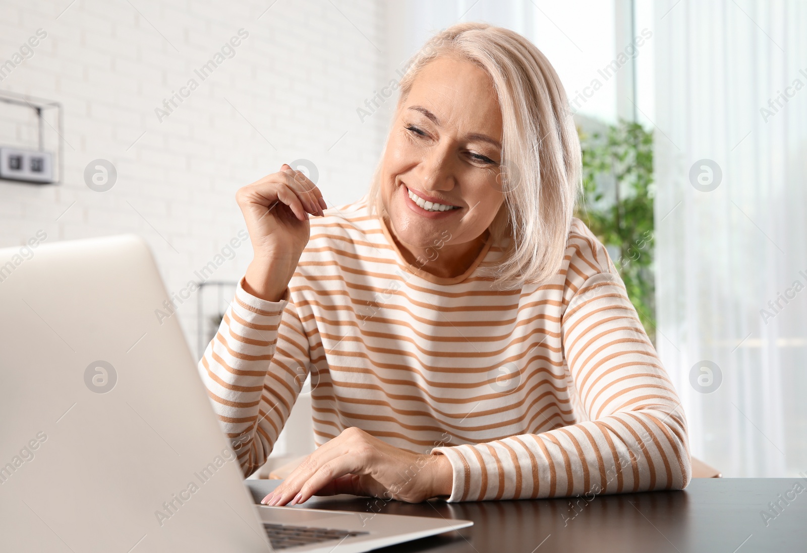 Photo of Mature woman using video chat on laptop at home