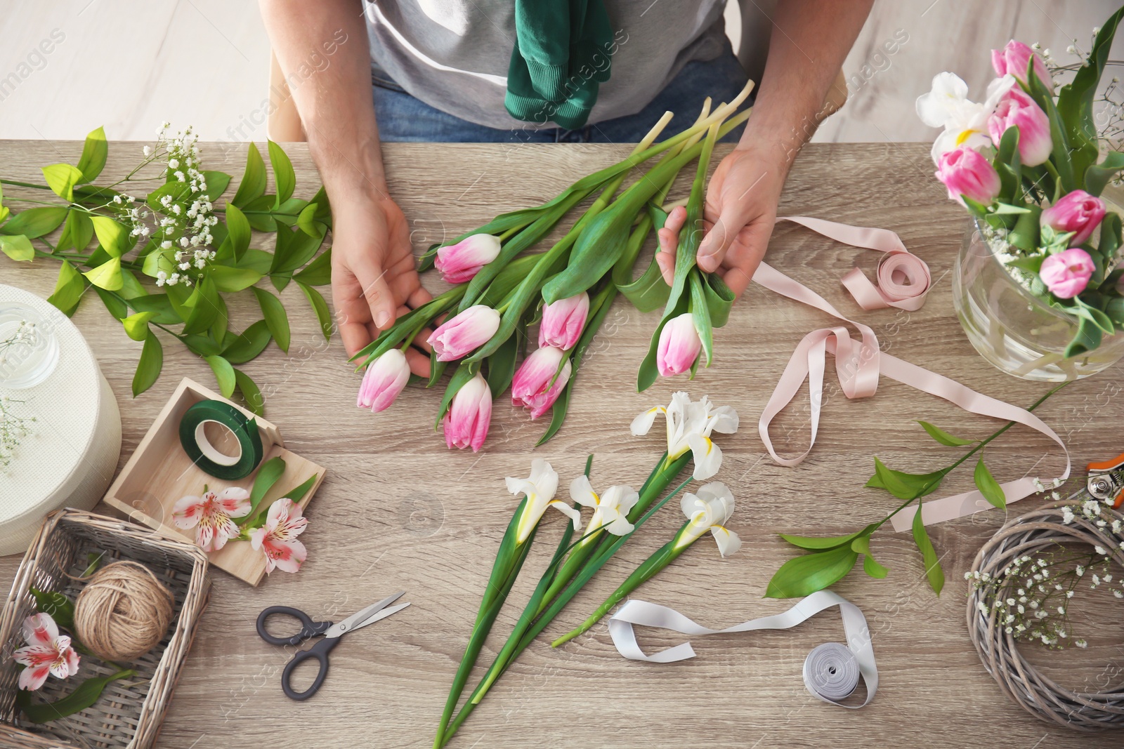 Photo of Male decorator creating beautiful bouquet at table, top view