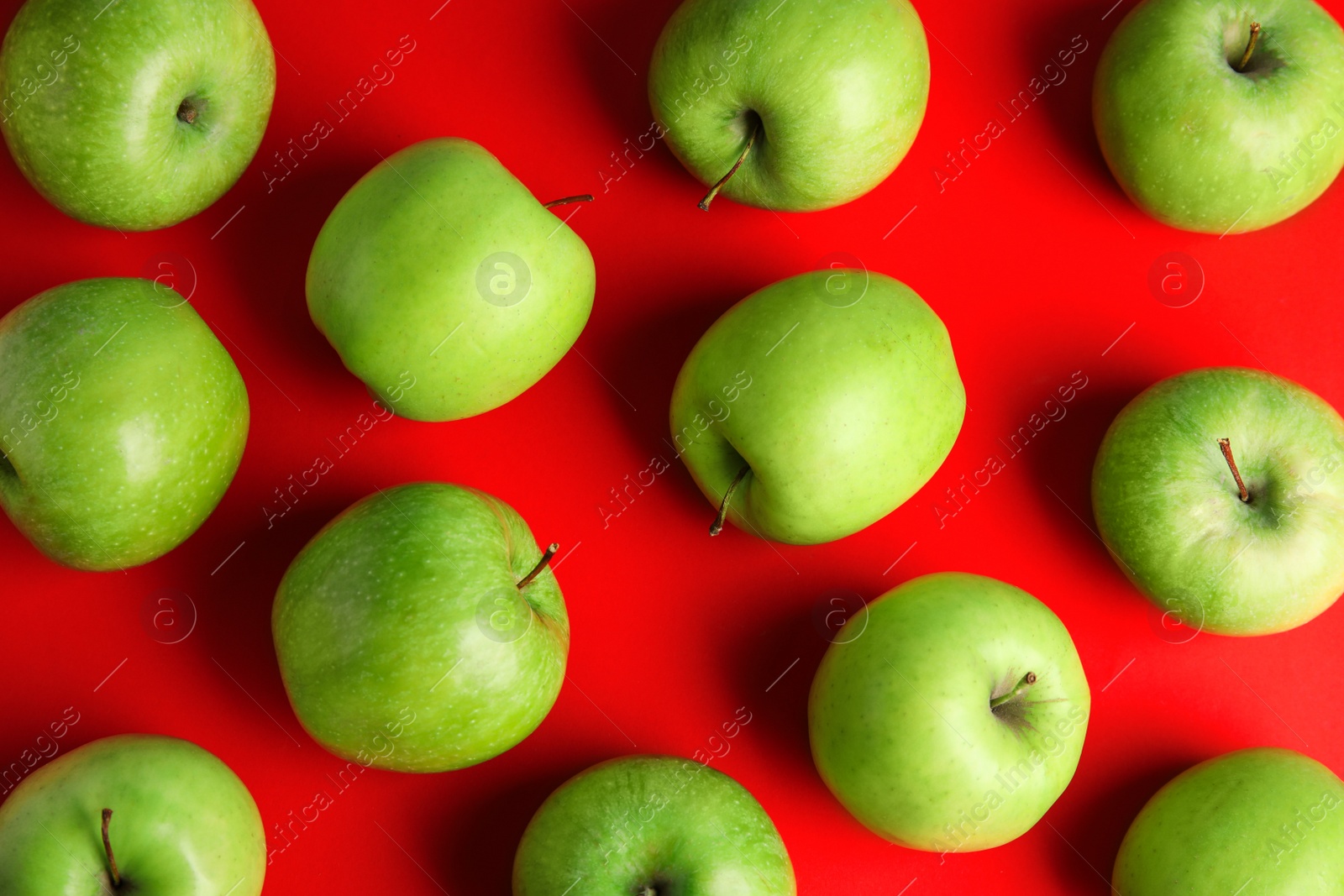 Photo of Flat lay composition of fresh ripe green apples on red background