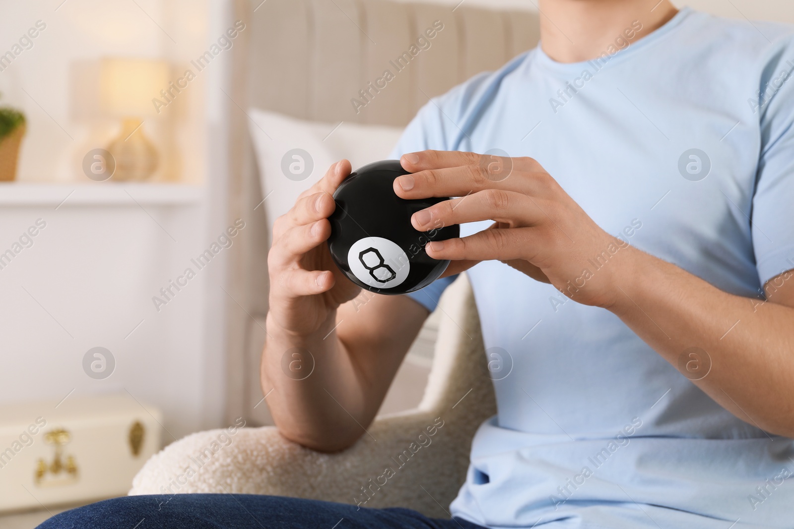 Photo of Man holding magic eight ball indoors, closeup