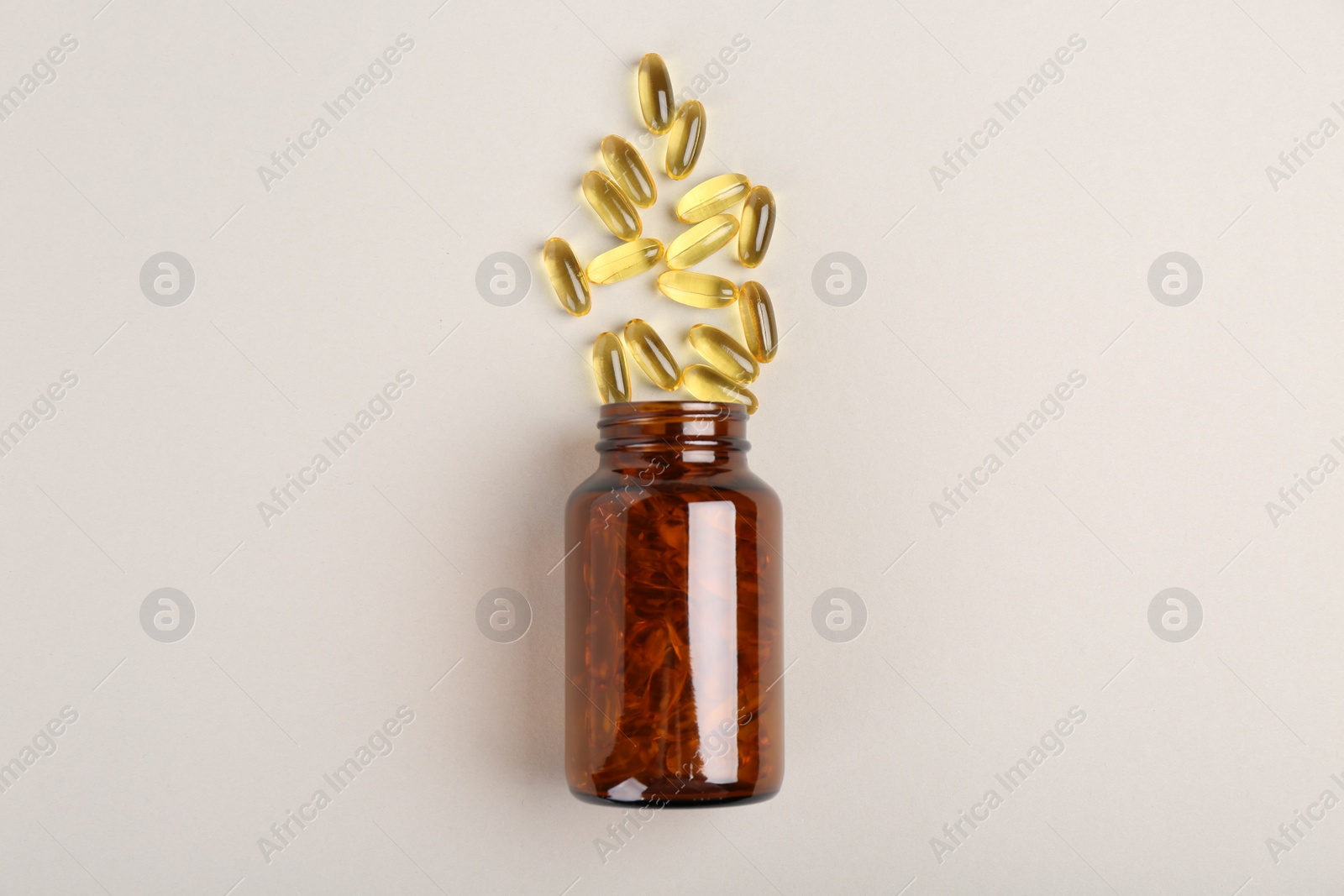 Photo of Bottle and vitamin capsules on light grey background, top view