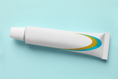 Photo of Tube of ointment on light blue background, top view. Space for text