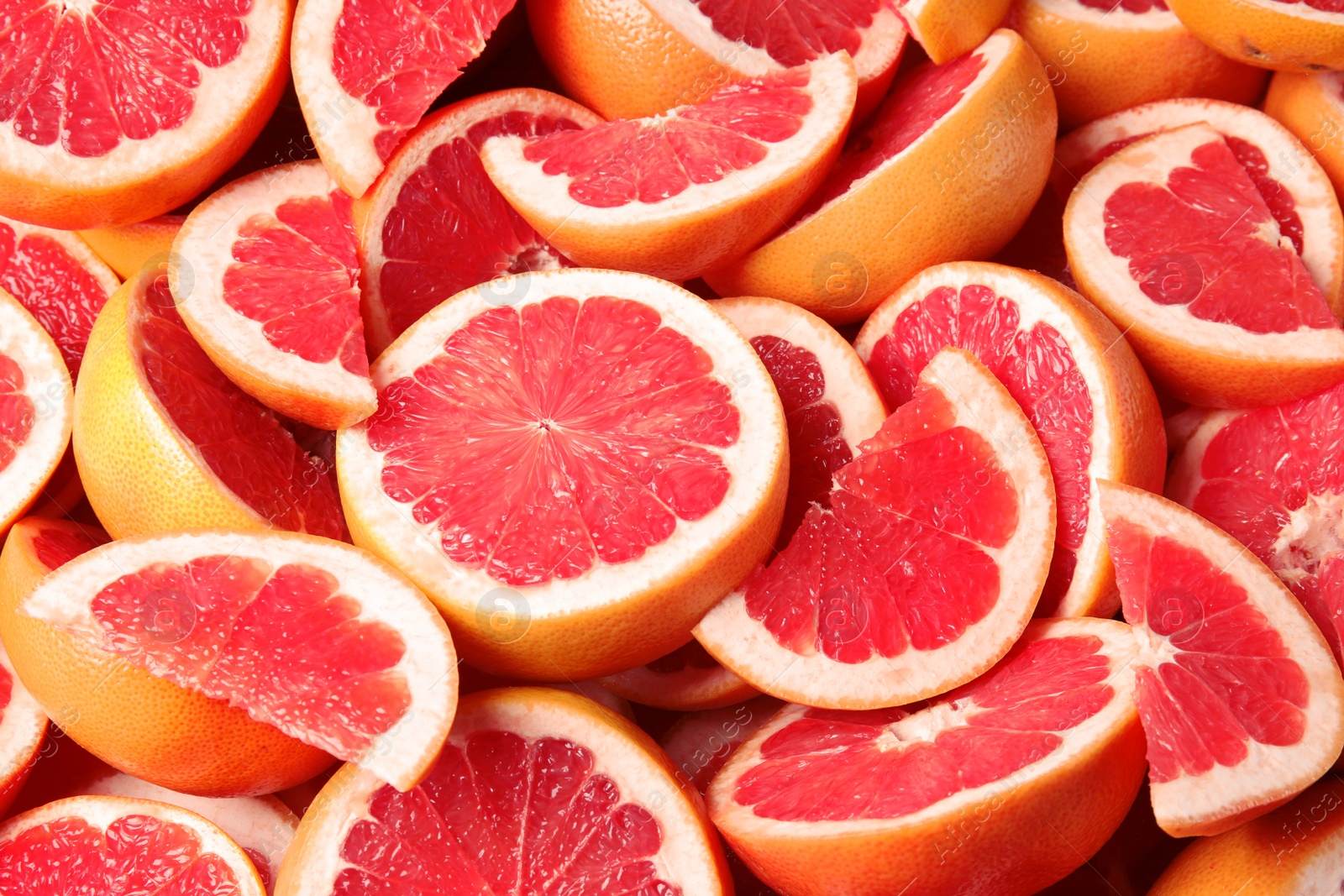 Photo of Many sliced fresh ripe grapefruits as background, closeup