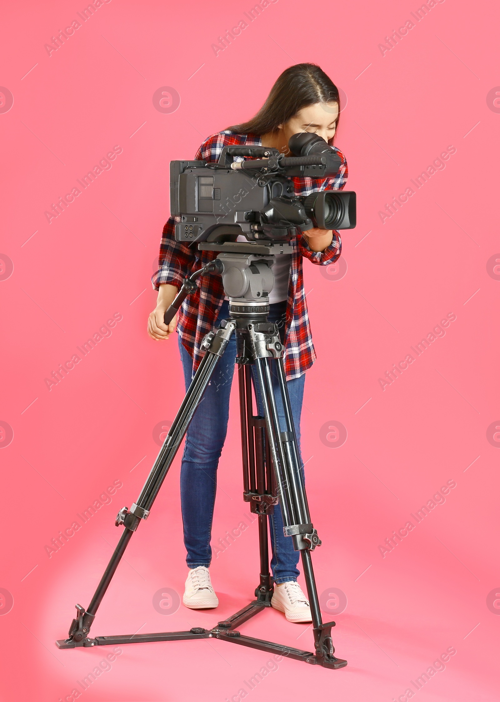 Photo of Operator with professional video camera on pink background