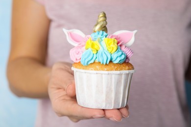 Photo of Woman holding cute sweet unicorn cupcake, closeup