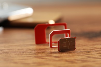 Red multi SIM card on wooden table, closeup