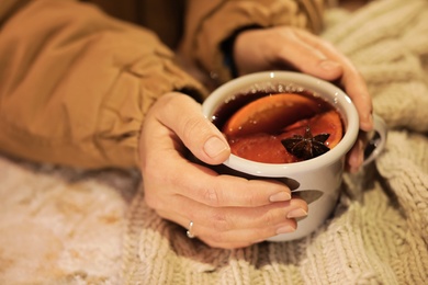 Photo of Woman with cup of mulled wine at table, closeup