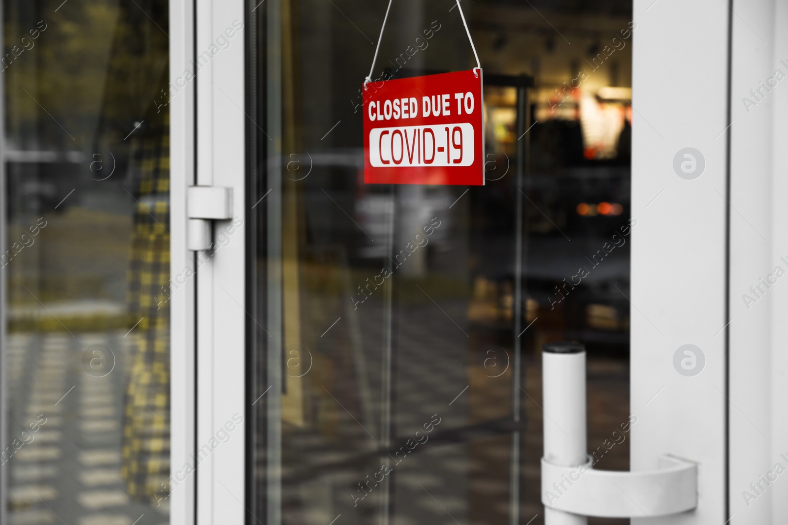 Photo of Red sign with words "Closed Covid-19" hanging on glass door