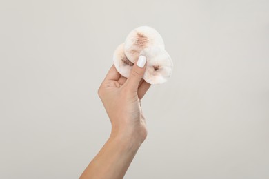 Woman with dirty cotton pads after removing makeup on light grey background, closeup