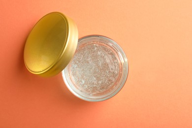 Photo of Jar of cosmetic gel on pale orange background, top view. Space for text
