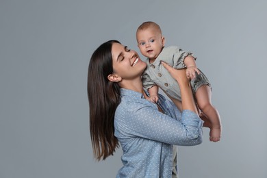 Photo of Beautiful mother with her cute baby on grey background