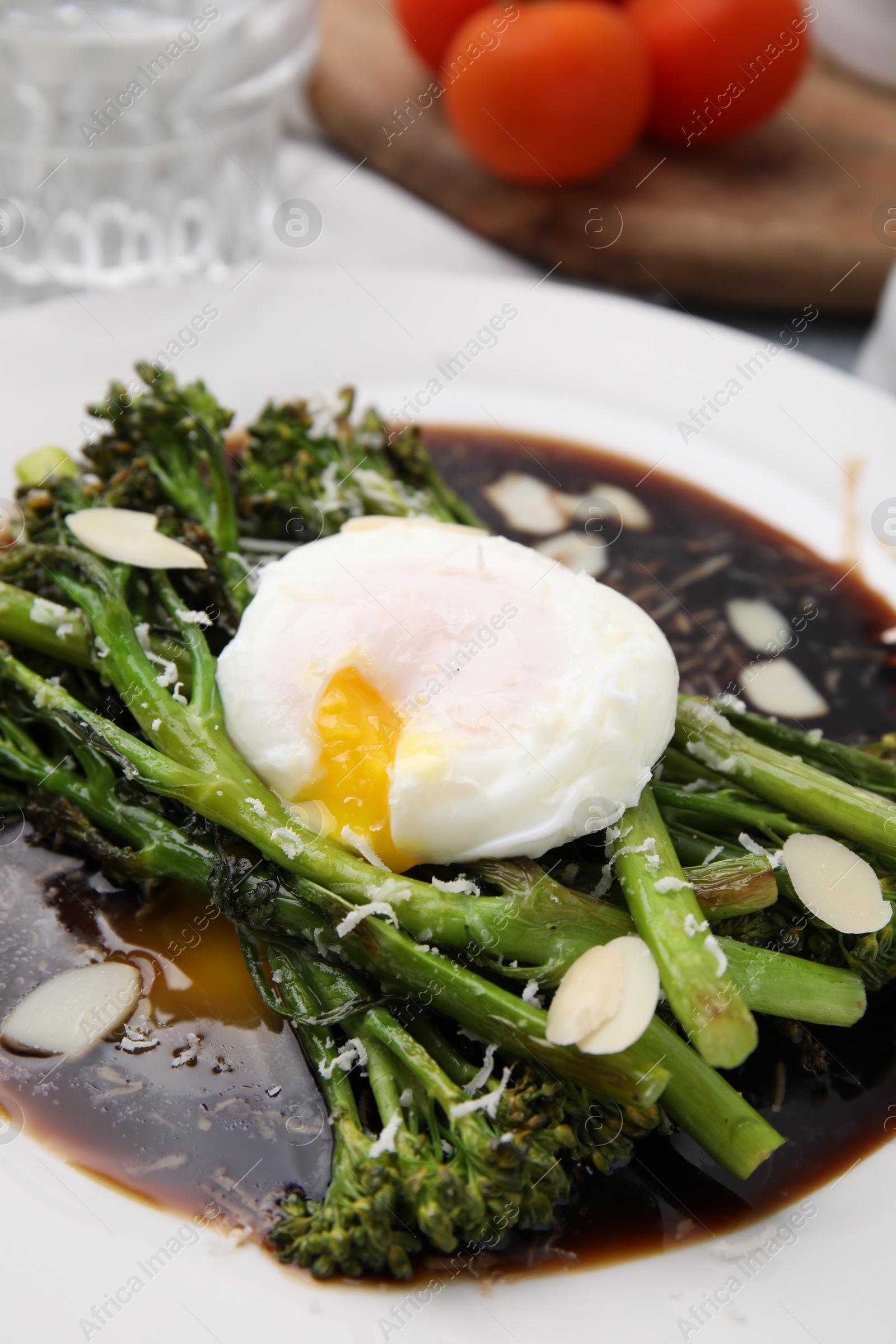 Photo of Tasty cooked broccolini with poached egg and sauce on plate, closeup