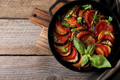 Photo of Delicious ratatouille on wooden table, top view. Space for text