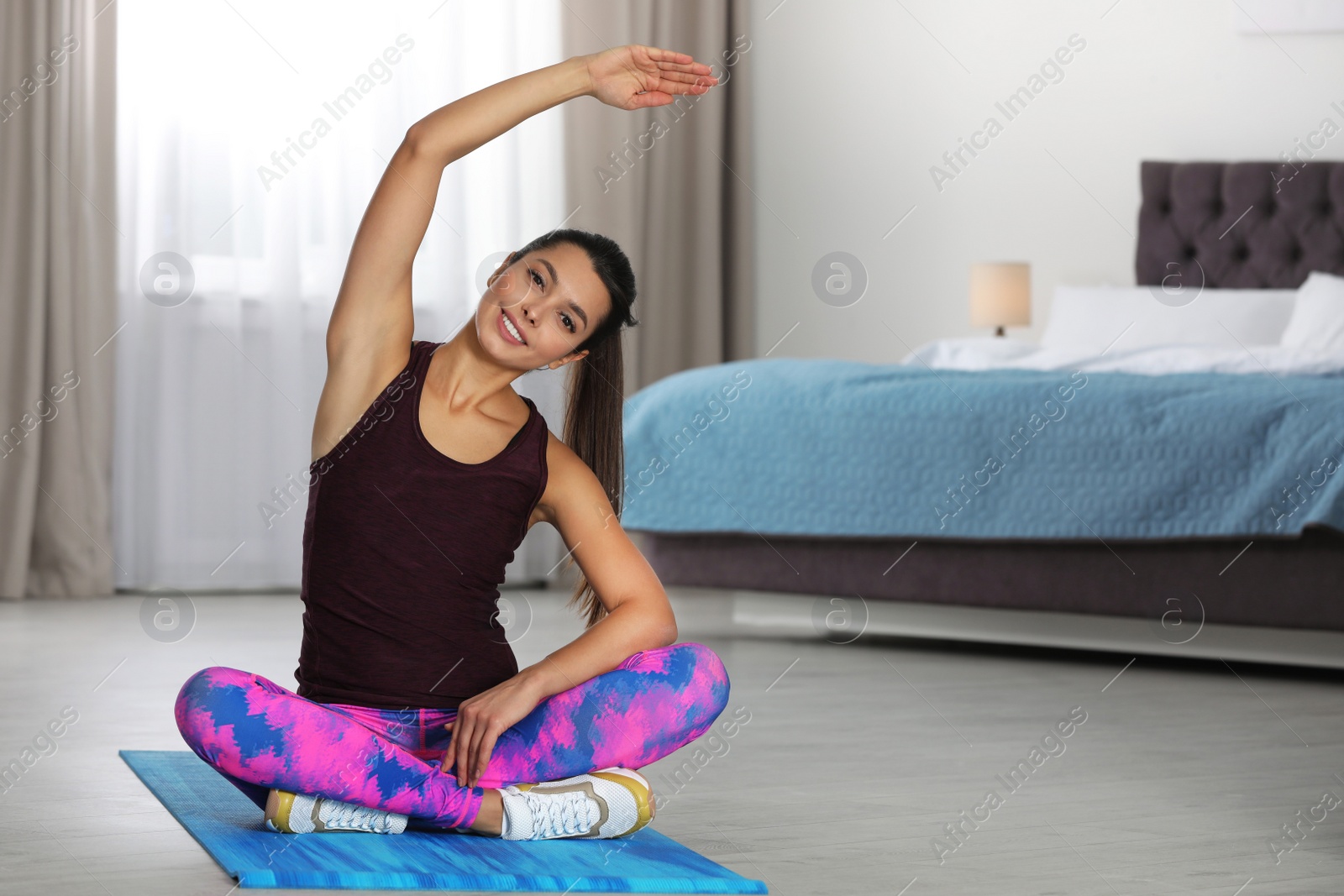 Photo of Young woman in fitness clothes doing exercise at home. Space for text